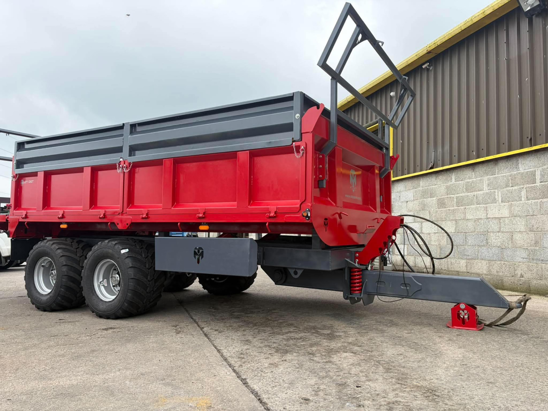 Red MT Plant 12T DST trailer side profile with sprung drawbar in the yard